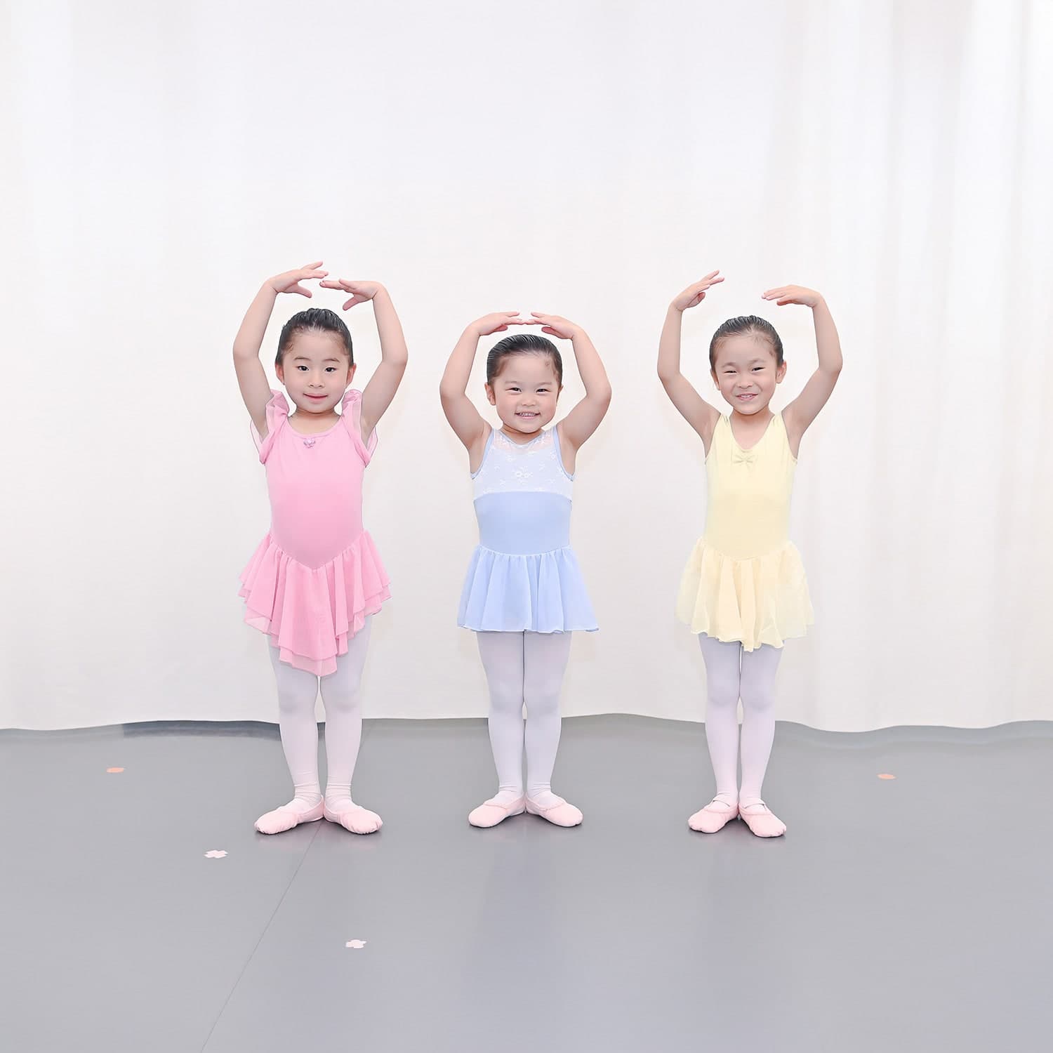 両手を頭の上に上げてポーズをとる3人の子どもたち